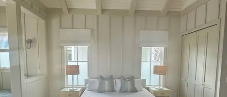 A bedroom with a bed, a ceiling fan, a nightstand, a dresser, and a window with blinds.
