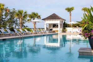 A pool area with lounge chairs and umbrellas, surrounded by palm trees and a gazebo. - “The Eagles Nest” (3035 Southerly Way) 2 person creekside bungalow at Kiawah River ~ (Johns Island)