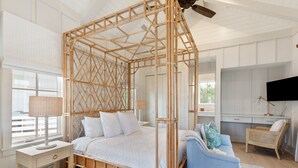 Una habitación con cama con dosel, un sofá azul, un televisor y una ventana con persianas.