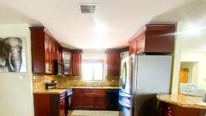 A kitchen with wooden cabinets, a stainless steel refrigerator, and a window providing natural light.