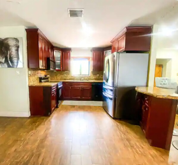 A kitchen with wooden cabinets, a stainless steel refrigerator, and a window providing natural light.