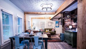 Un comedor con mesa y sillas de madera, un sofá y una pared de ladrillo.