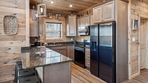 Una cocina moderna con paredes de madera, encimeras de granito, electrodomésticos de acero inoxidable y una ventana con persianas.