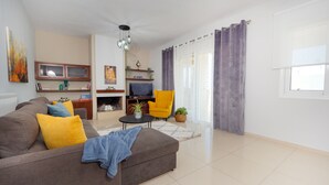 Una sala de estar moderna con un sofá, sillones, una mesa de centro y un televisor.