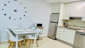 A modern kitchen with a dining table set for two, a microwave, a refrigerator, and a dishwasher. - Sun apartment (Viveiro)