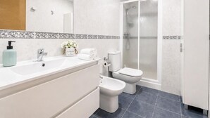 A modern bathroom with a large mirror, a sink, a toilet, and a shower. - Sun apartment (Viveiro)