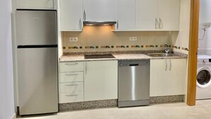 A kitchen with a stainless steel refrigerator, dishwasher, and washing machine. - Sun apartment (Viveiro)