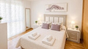 A hotel room with a large bed, two bedside tables with lamps, a mirror, and a window with sheer curtains. - Sun apartment (Viveiro)