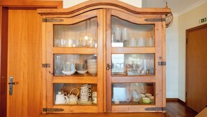 Un buffet en bois doté de portes en verre, renfermant divers objets en verre et de la vaisselle.