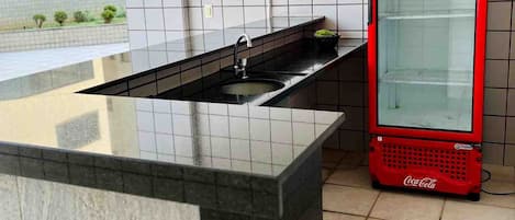 Una cocina moderna con encimera negra, un fregadero y un refrigerador rojo de Coca-Cola.