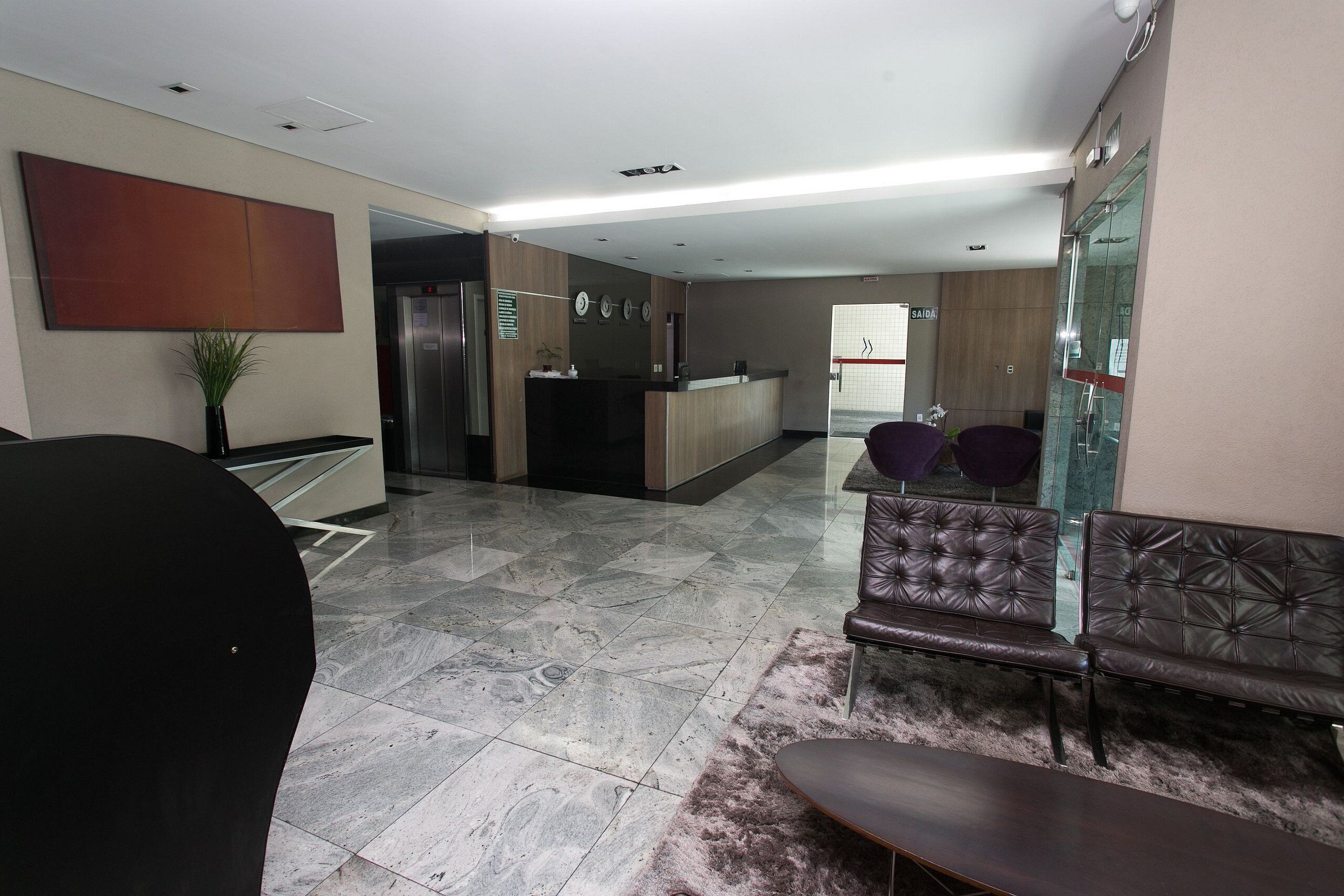 A modern lobby with a reception desk, seating area, and a glass partition.