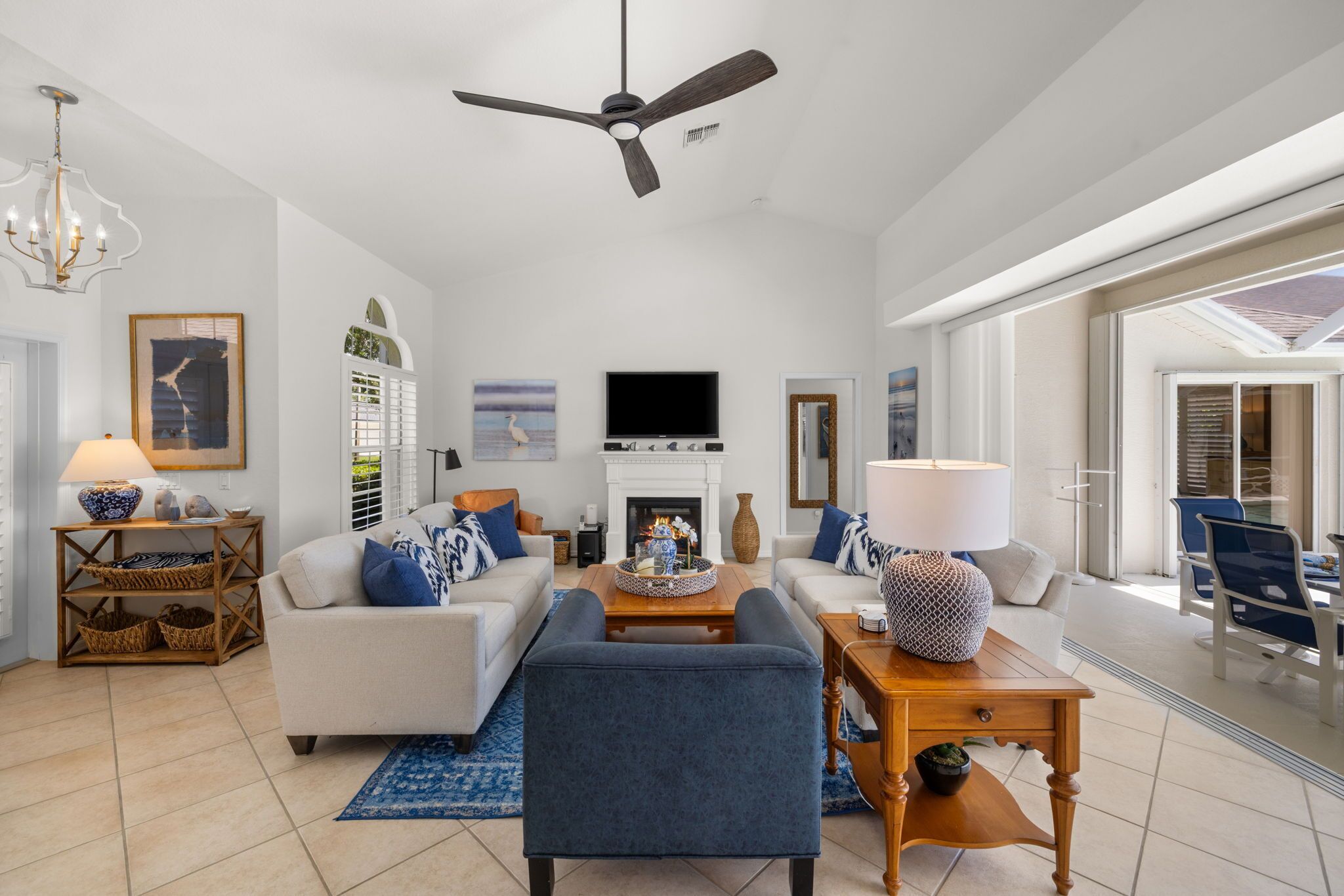 A spacious living room with a fireplace, a ceiling fan, and a large TV.