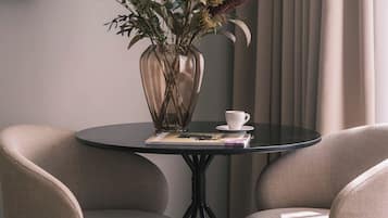 Una habitación moderna con una mesa redonda, dos sillas, un florero con flores secas y un control remoto sobre la mesa.