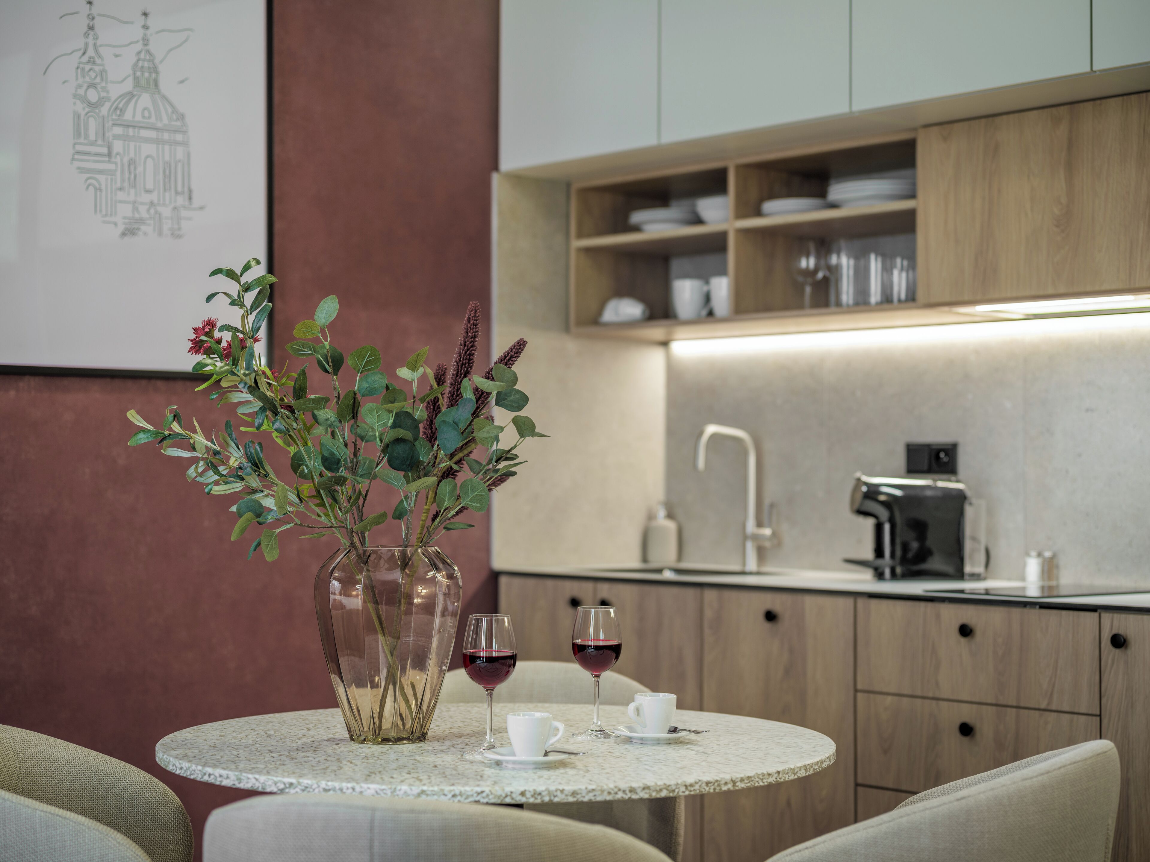 Une cuisine moderne avec un plan de travail en marbre, un vase orné de feuillage verdoyant et deux verres à vin.