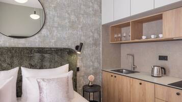 A modern bedroom with a large bed, a round mirror, and a small bedside table with a vase.
