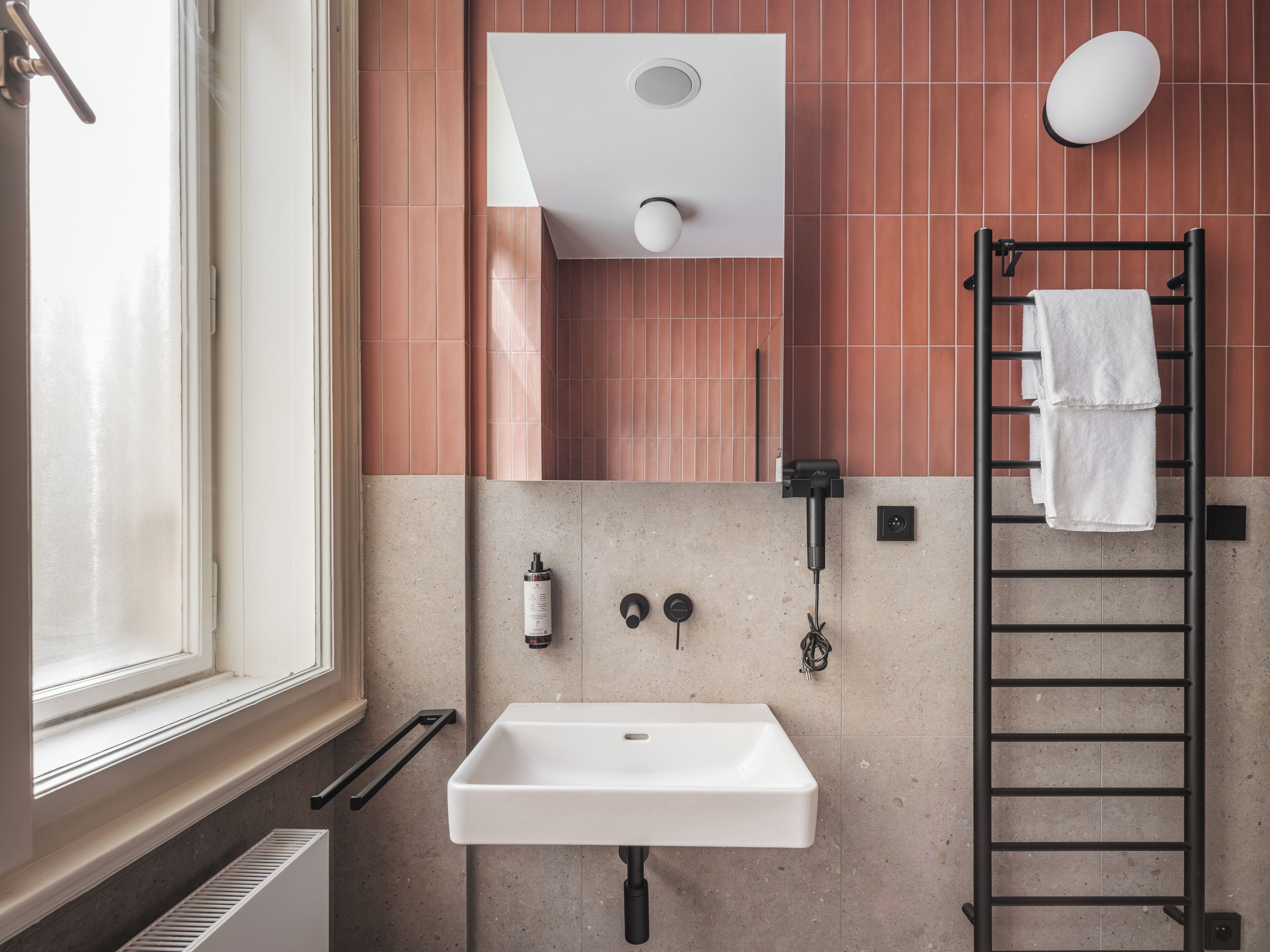 A bathroom with a white sink, a towel rack, and a window.