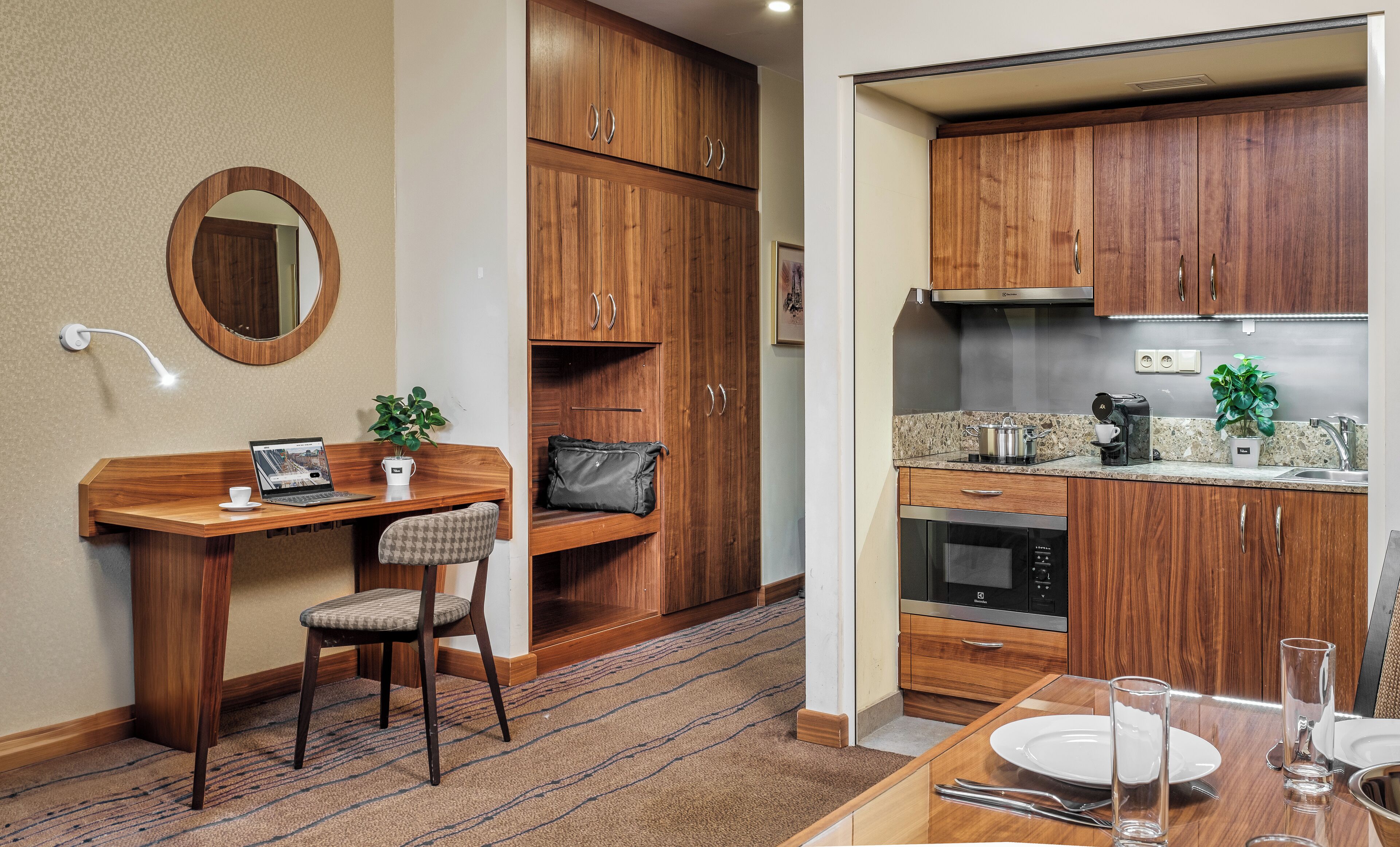 A compact kitchen with wooden cabinets, a built-in oven, and a dining area with a table set for two.