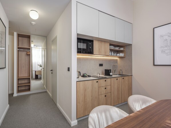 A modern kitchen with wooden cabinets, a built-in microwave, and a sink. - Crown Palace Apartments by Adrez (Prague)