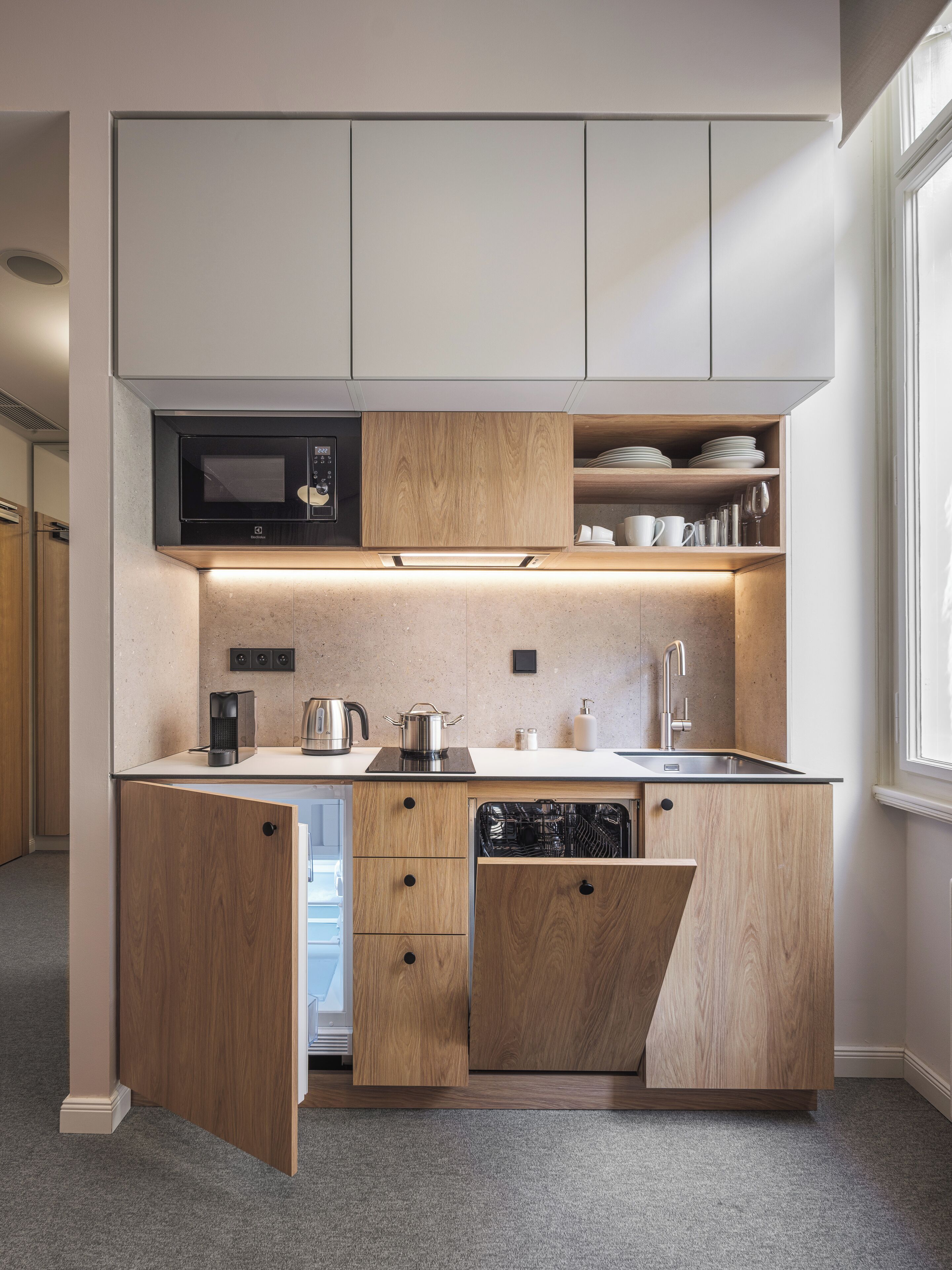 A compact kitchen with built-in appliances, a microwave, and a sink.