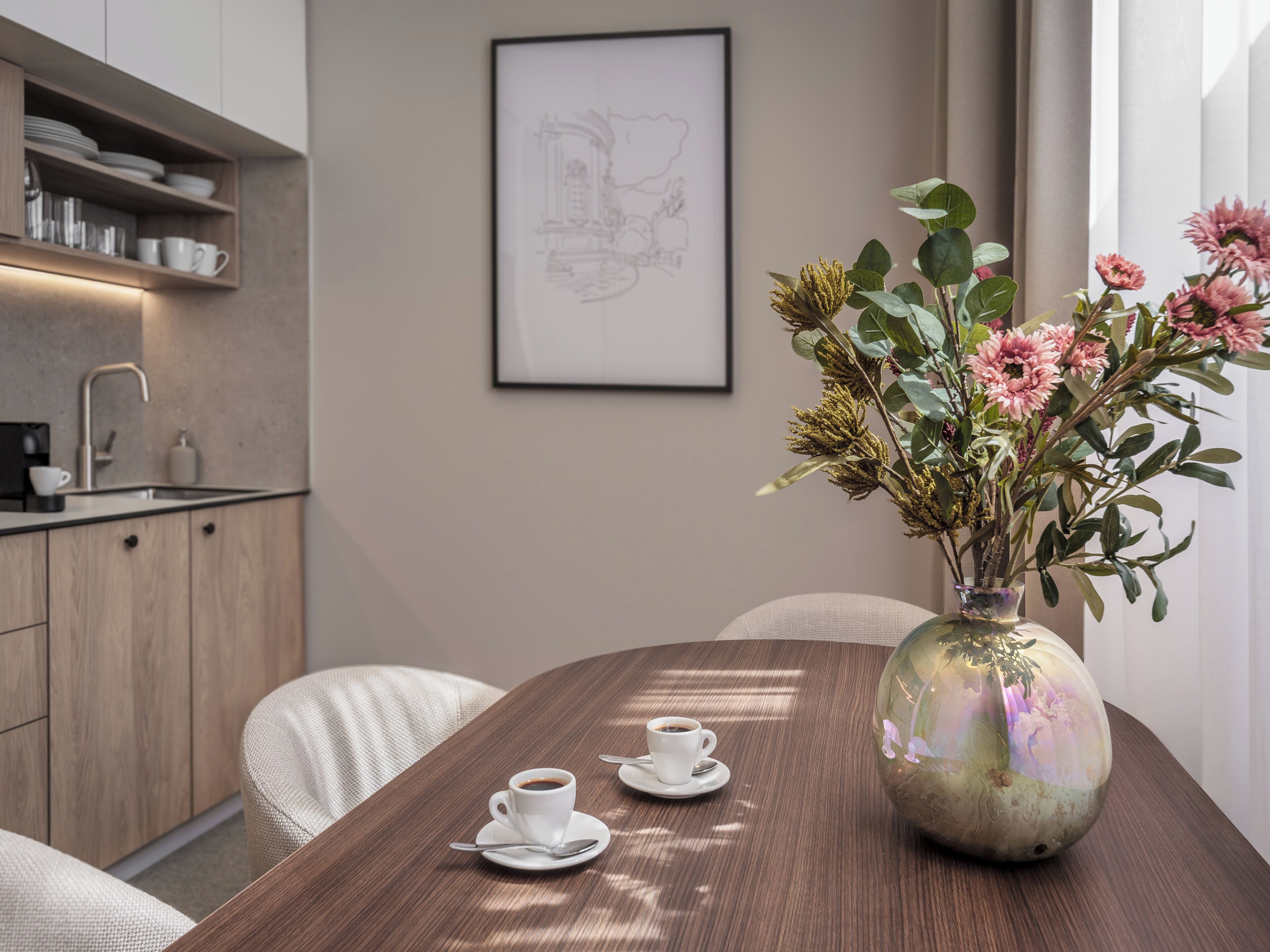 Een moderne keuken met een eethoek, een vaas met bloemen en een lijst met een foto aan de muur.