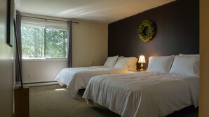 Ein Hotelzimmer mit zwei Betten, einem Vorhangfenster, einem an der Wand befestigten Kranz und einer Nachttischlampe.