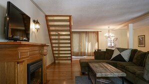 Ein Wohnzimmer mit Kamin, einer Holztreppe und einem Sofa.
