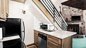 Une cuisine avec une cheminée en pierre, des armoires en bois et un fourneau moderne.