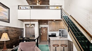 Un intérieur moderne comprenant un coin repas, une cuisine et un escalier menant à une mezzanine.