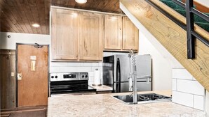 Une cuisine moderne avec des meubles en bois, un réfrigérateur en acier inoxydable et un plan de travail en granit.