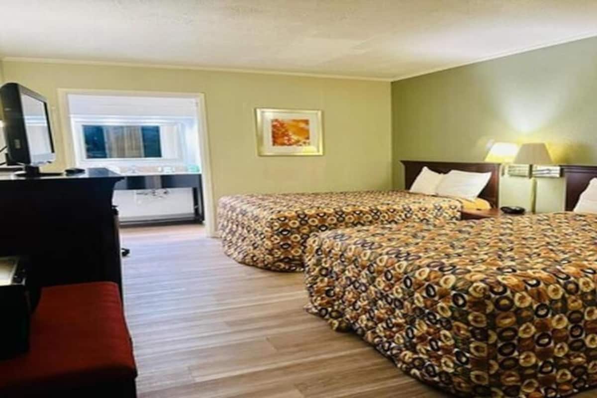 Ein Hotelzimmer mit zwei Betten, einem Schreibtisch und einem Stuhl.