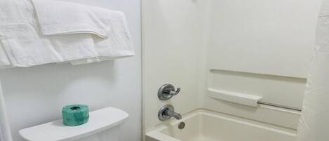 Ein Badezimmer mit Toilette, Toilettenpapierrolle und Badewanne.