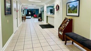 A hotel lobby with a tiled floor, a reception desk, a bench, and framed pictures on the walls. - Astoria North Extended Stay (Danville)