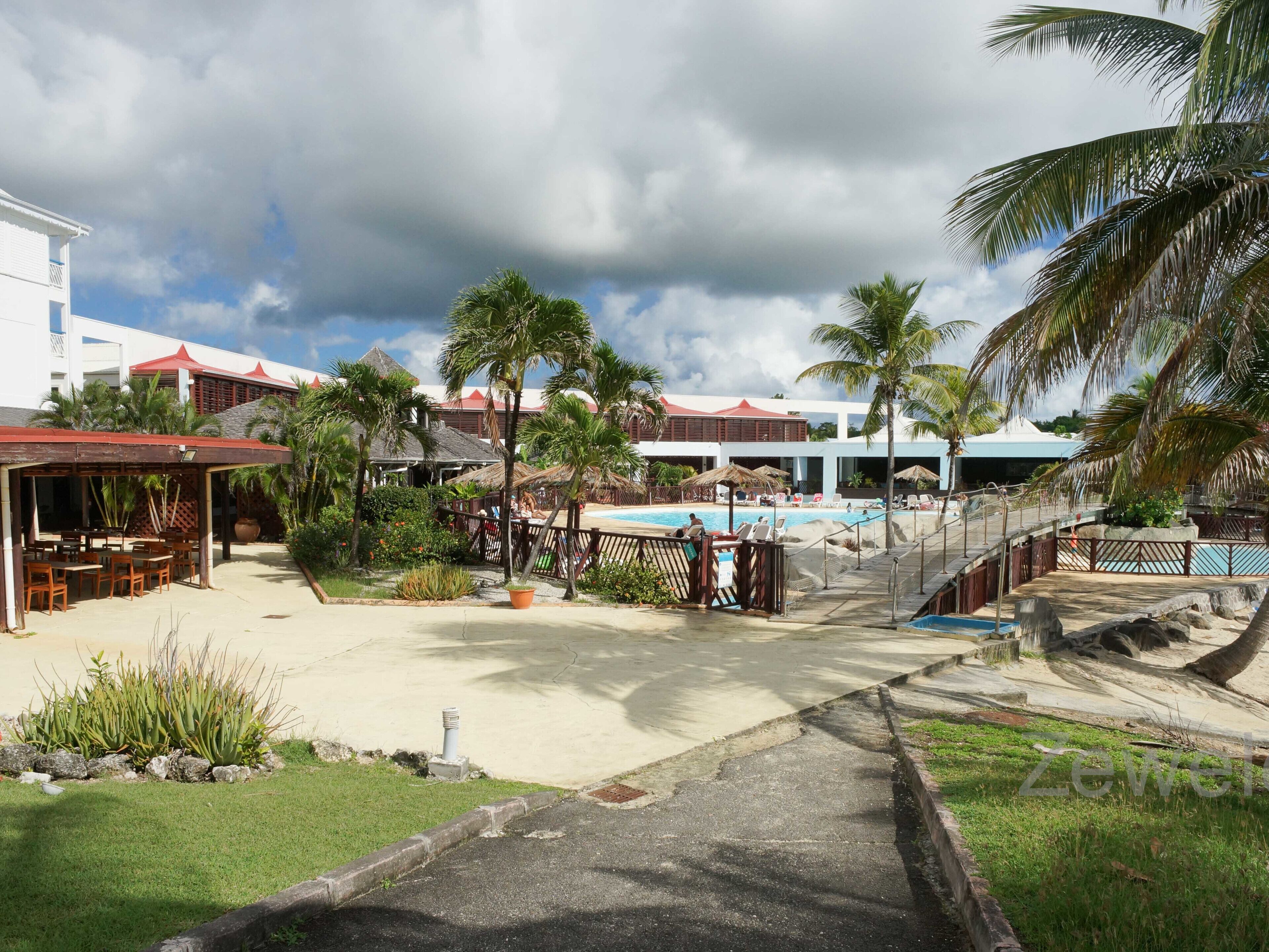 Ein Resort mit Swimmingpool, Sitzgelegenheiten im Freien und Palmen.