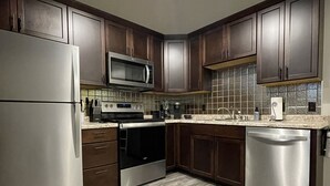 Una cocina moderna con armarios de madera oscura, electrodomésticos de acero inoxidable y un respuesto de azulejos.