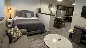 Un dormitorio moderno con una cama, mesita de noche, lámpara y una mesa redonda.