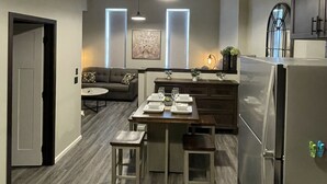 Una cocina moderna con comedor, ventilador de techo, luces colgantes y refrigerador.