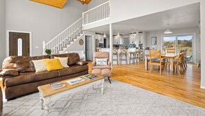 A spacious living area with a brown leather sofa, a wooden coffee table, and a high ceiling with exposed beams. - 20 ft swim spa! 5 bed, 4 bath, hot tub, 5 acres, game room, north CO Springs! (Colorado Springs)