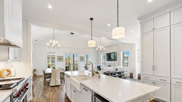 A modern kitchen with white cabinetry, stainless steel appliances, and pendant lighting.