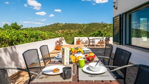 Une terrasse avec une table dressée pour le petit-déjeuner, donnant sur un paysage verdoyant.