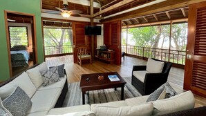 Uma sala de estar ampla com teto de madeira, um conjunto de sofá, uma mesa de centro e uma TV fixada na parede.