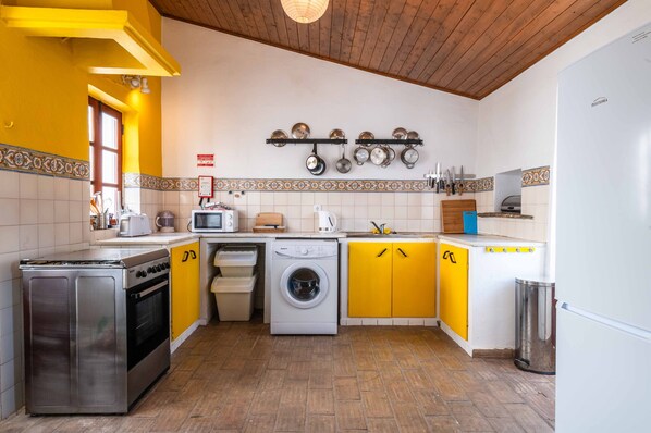 A compact kitchen with a washing machine, a stove, and a microwave. - A perfect house for a combined group such as a large family and for piano lovers (Santa Catarina Fonte Bispo)