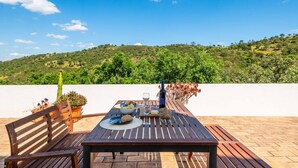 Une table en bois installée à l’extérieur, offrant une vue sur une colline verdoyante.