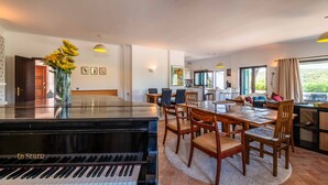 Un coin repas avec un piano, des chaises en bois et une table.