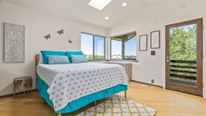 Une chambre à coucher avec un lit, des fenêtres et une vue sur la verdure.