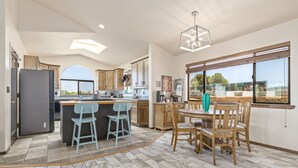 Une cuisine moderne dotée d’un îlot central, de tabourets de bar et d’une table à manger avec des chaises.