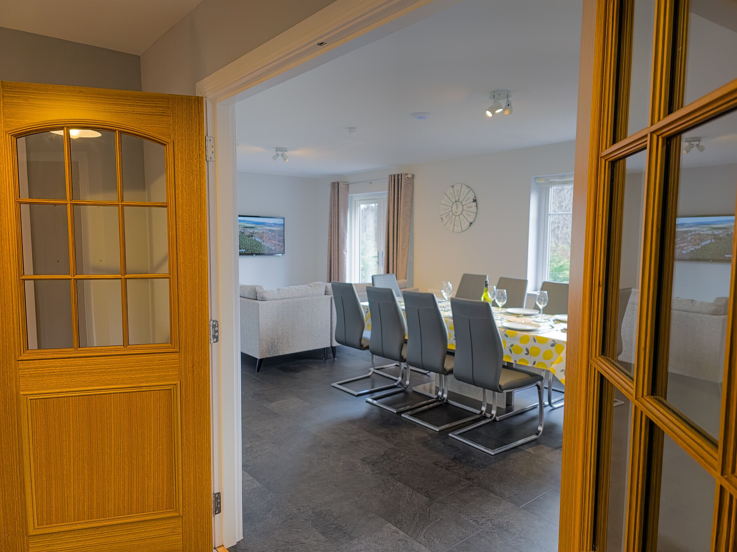 A dining area with a table set for six, a sofa, and a TV in the background.