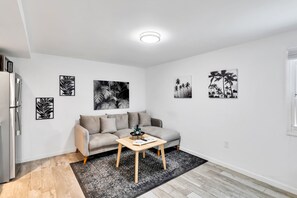 Una sala de estar moderna con un sofá gris, una mesa de centro de madera y obras de arte blanco y negro en las paredes.