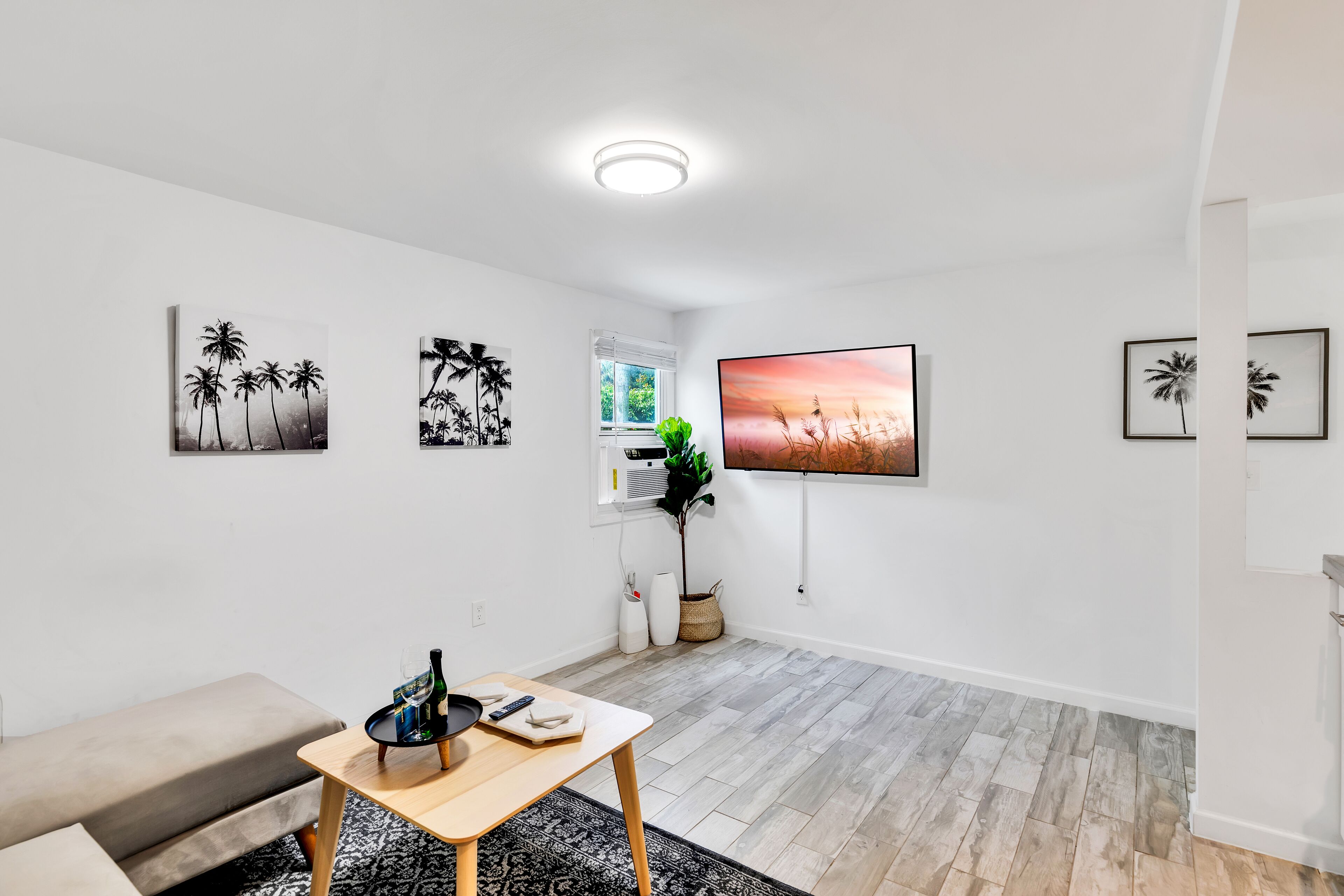 A modern living room with a sofa, a wooden coffee table, and a TV mounted on the wall.