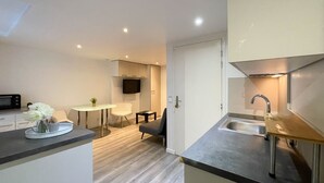 A modern kitchen with a built-in oven, a sink, and a dining area with a table and chairs. - Belvédère vieille ville proche du château (Annecy)