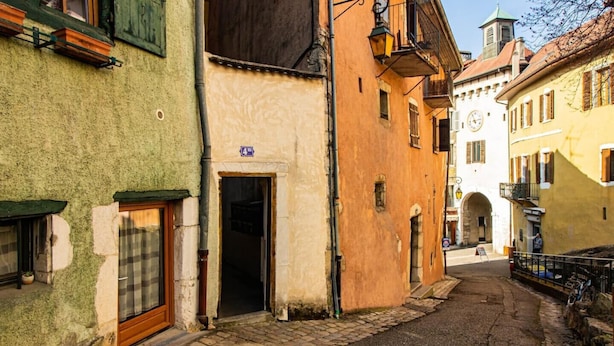 A narrow cobblestone street lined with historic buildings, featuring a mix of architectural styles and a visible sign indicating a public space. - Belvédère vieille ville proche du château (Annecy)
